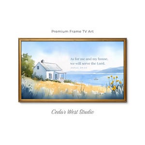May include: A framed digital artwork featuring a watercolor landscape of a white house by a blue lake with yellow wildflowers in the foreground. The text reads: As for me and my house, we will serve the Lord. Joshua 24:15. The frame is gold-toned.