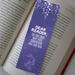 Puede incluir: Marcapáginas morado con el texto "DEAR READER, GET OUT YOUR MAP, PICK SOMEWHERE AND JUST RUN." Presenta una ilustración de pez koi y detalles florales. Ideal para amantes de la lectura.