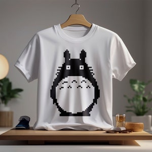 May include: White t-shirt with a black pixelated graphic of Totoro from the movie My Neighbor Totoro.