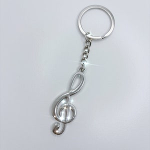 Op de afbeelding: Een zilveren sleutelhanger in de vorm van een vioolsleutel met een zilveren ketting en een zilveren ring.