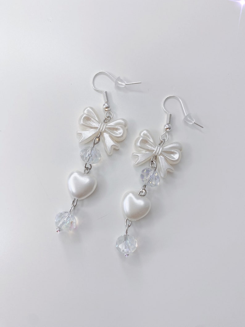 White earrings with a pearl bow, iridescent earrings and pearl hearts.