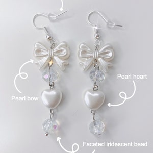 White earrings with a pearl bow, iridescent earrings and pearl hearts with a description about the materials.
