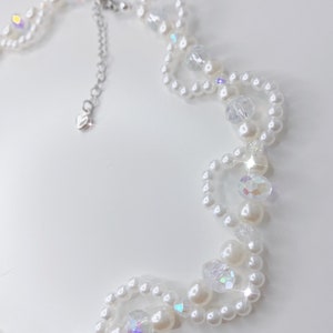 A white pearl twirl necklace with iridescent beads and pearl bows.