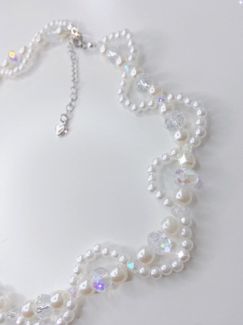 A white pearl twirl necklace with iridescent beads and pearl bows.