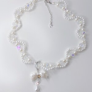 A white pearl twirl necklace with iridescent beads and pearl bows.