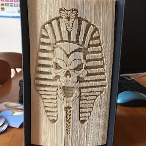Op de afbeelding: Een boekkunst sculptuur van een schedel die een farao's hoofdtooi draagt. De sculptuur is gemaakt van de pagina's van een boek die gevouwen en gelaagd zijn om een 3D-effect te creëren.