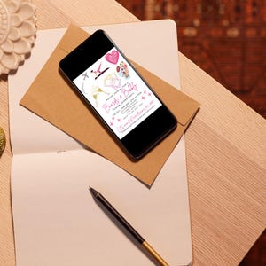 May include: A smartphone displaying a pink and white invitation for a "Brunch & Bubbles" event. The invitation features illustrations of champagne flutes, a plane, a crown, and a heart. The text on the invitation reads "Please join us for a Brunch & Bubbles" and includes the date, time, and location of the event.