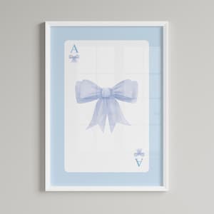 Puede incluir: Impresión enmarcada con una ilustración de acuarela de la carta del As de Corazones. La carta tiene un borde y un fondo azul claro. La carta del As de Corazones tiene un gran lazo azul en el centro y lazos más pequeños arriba y abajo.
