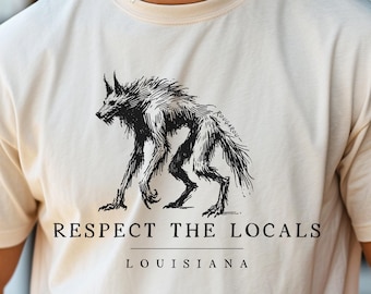 May include: A white t-shirt with a black graphic of a werewolf and the text "Respect the Locals Louisiana".
