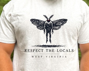 May include: A heather grey t-shirt with a black and white illustration of a moth with red eyes. The text "Respect the Locals" and "West Virginia" is printed below the moth.