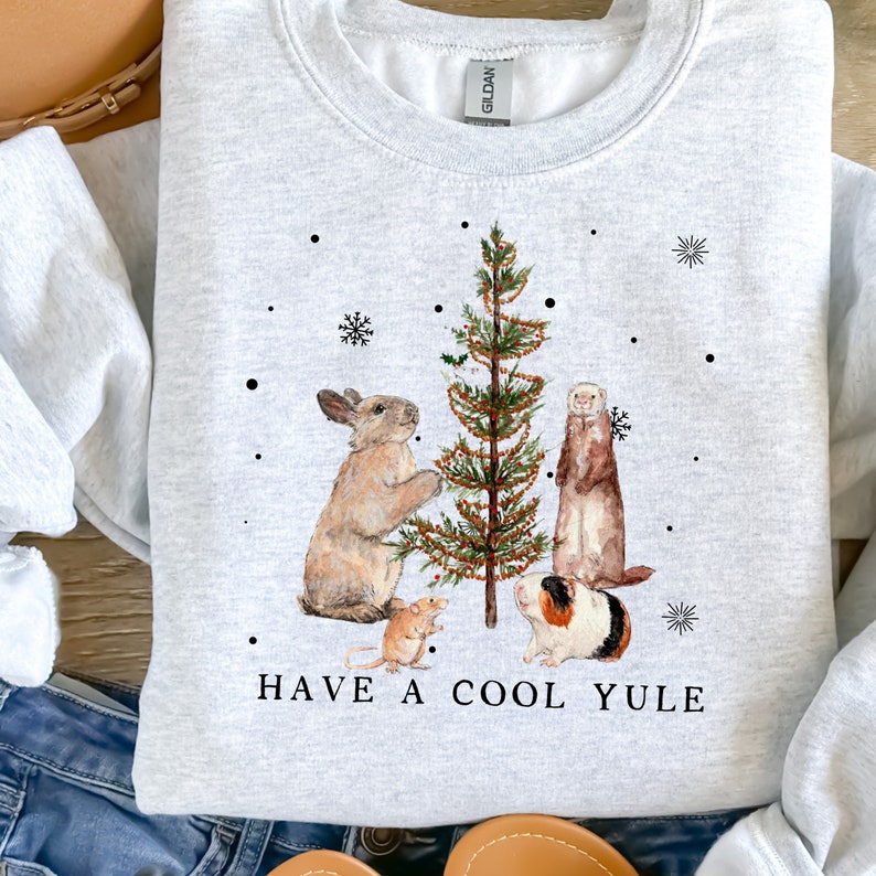 May include: A gray sweatshirt with a white graphic of a rabbit, ferret, guinea pig, and mouse decorating a Christmas tree. The text "HAVE A COOL YULE" is printed below the graphic.