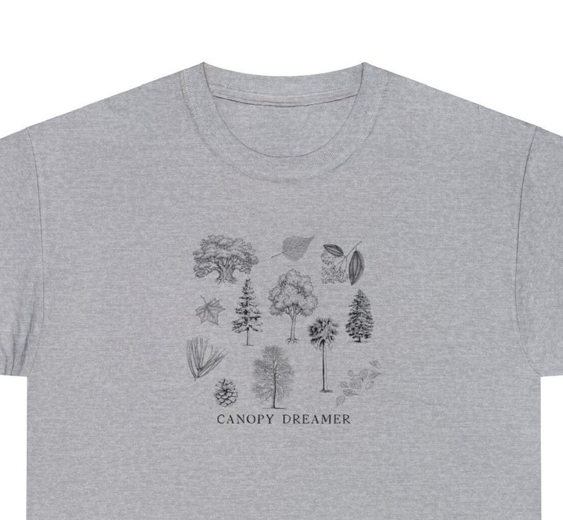 Może przedstawiać: Szary t-shirt z nadrukiem czarno-białej ilustracji r&oacute;żnych drzew i liści. Pod ilustracją znajduje się napis "CANOPY DREAMER".