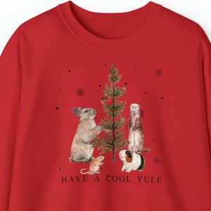 May include: Red Christmas sweatshirt with a graphic of a rabbit, ferret, guinea pig, and mouse standing around a Christmas tree. The text "HAVE A COOL YULE" is printed below the graphic.