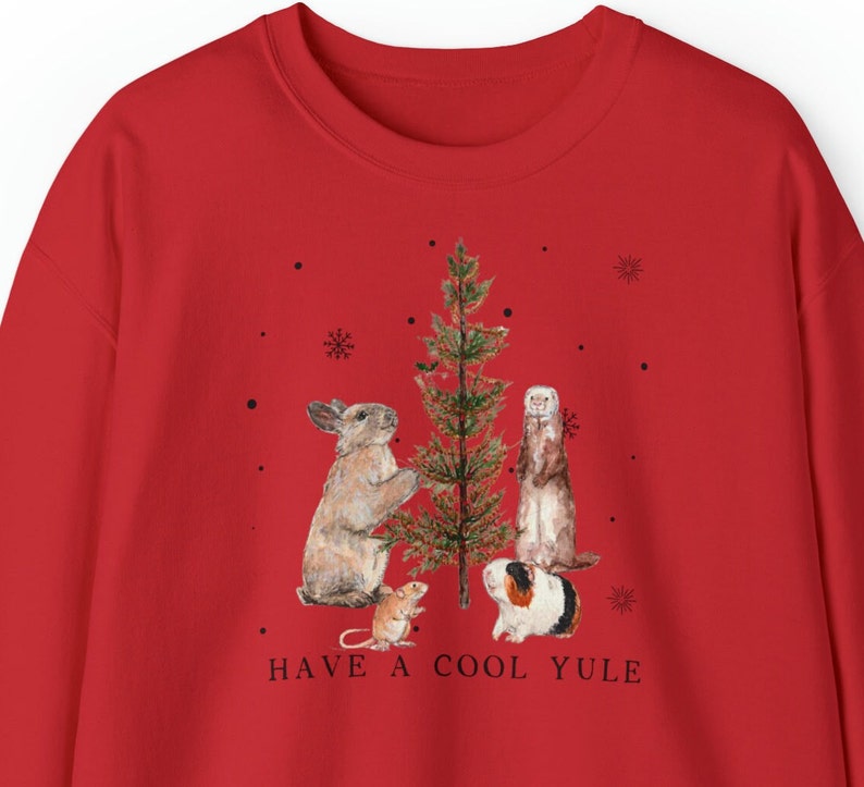 May include: Red Christmas sweatshirt with a graphic of a rabbit, ferret, guinea pig, and mouse standing around a Christmas tree. The text "HAVE A COOL YULE" is printed below the graphic.