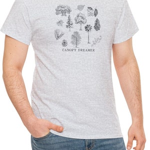 Może przedstawiać: Szary t-shirt z nadrukiem czarno-białej ilustracji r&oacute;żnych drzew i liści. Pod ilustracją znajduje się napis "CANOPY DREAMER".