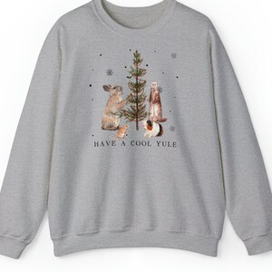 May include: A gray sweatshirt with a festive design featuring a rabbit, ferret, guinea pig, and a mouse decorating a Christmas tree. The text "HAVE A COOL YULE" is printed below the animals.