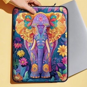 May include: A colorful laptop sleeve featuring a detailed mandala-style elephant with purple, pink, yellow, and blue accents. The elephant is surrounded by floral designs and intricate patterns.