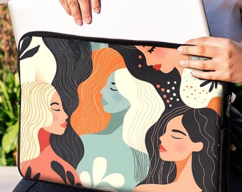 May include: A laptop sleeve with a colorful abstract design featuring multiple women's faces. The sleeve is black with a white zipper and is being held by a person.
