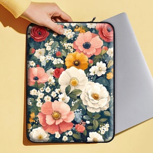 Könnte beinhalten: Eine Laptop-Hülle mit Blumenmuster, dunkelblauem Hintergrund und verschiedenen bunten Blumen, darunter rosa, weiß, gelb und rot.