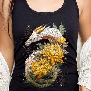 Könnte beinhalten: Schwarzes Tanktop mit einem Design eines weißen und goldenen Drachen, der sich mit gelben Blumen und grünen Blättern verwebt. Der Drache hat detaillierte Schuppen und ein stilisiertes Aussehen. Das Tanktop ist ärmellos und hat einen Rundhalsausschnitt.