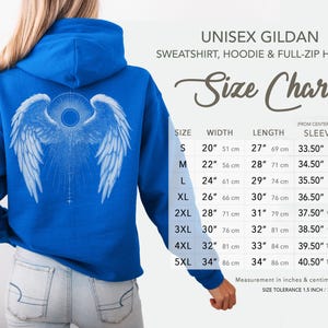 May include: A royal blue unisex hoodie with a white angel wing design on the back. The image includes a size chart with measurements in inches and centimeters. The hoodie is a Gildan sweatshirt.