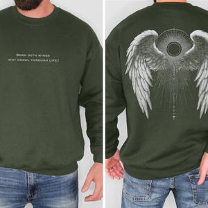 May include: Olive green sweatshirt with white text on the front that reads "BORN WITH WINGS WHY CRAWL THROUGH LIFE?". The back features a detailed white graphic of angel wings with a sunburst design. A crew neck sweatshirt.