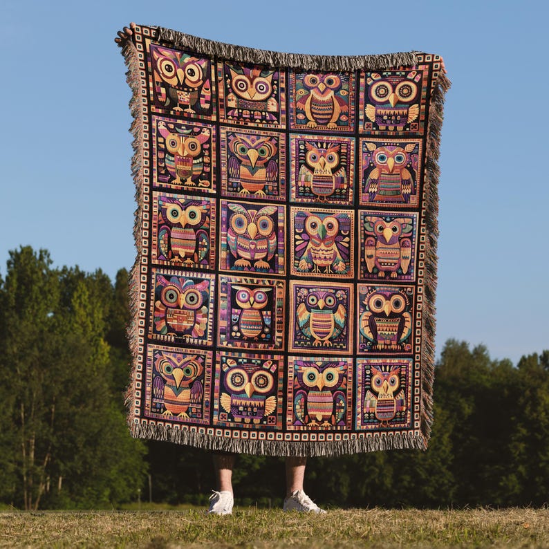 May include: A woven tapestry throw blanket with a geometric pattern of owls in various colors, including orange, yellow, green, blue, and purple. The blanket has a fringe border.