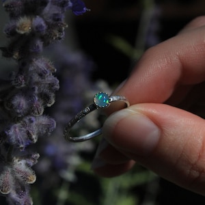May include: A silver ring with a delicate design and a green opal gemstone.