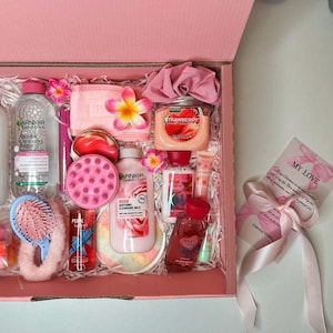 May include: A pink gift box filled with beauty products, including Garnier Micellar Cleansing Water, strawberry-scented items, and Pink Velvet body care. The box is decorated with pink flowers and a card that says "My Love."