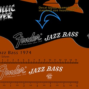 Könnte beinhalten: Metallisch silbernes Fender Jazz Bass 1974 Decal-Layout-Beispiel. Das Bild zeigt das Decal über einer Kopfplatte in Standardgröße. Enthält ein Lineal mit Zentimetern. Der Text "Jazz Bass" ist deutlich sichtbar.