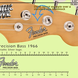 Può includere: Primo piano di una paletta Fender Precision Bass 1966 con logo argento metallizzato. L'immagine include un righello che mostra 23,00 cm e un esempio di layout adesivo.