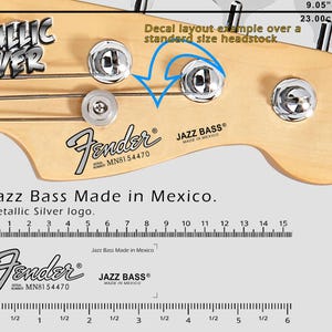 Könnte beinhalten: Nahaufnahme einer Fender Jazz Bass Kopfplatte mit Stimmwirbeln. Der Text "Metallic Silver" und "Jazz Bass Made in Mexico" ist zu sehen. Die Kopfplatte ist 23,00 cm breit.