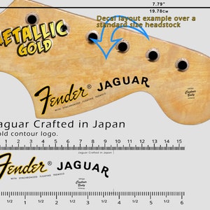 Könnte beinhalten: Ein Beispiel für das Layout eines Gitarrenkopfplatten-Aufklebers. Der Aufkleber ist goldfarben mit dem Text "METALLIC GOLD" und "Fender JAGUAR". Die Kopfplatte ist 19,78 cm breit und 7,79 Zoll breit. Der Text "Jaguar Crafted in Japan" ist ebenfalls sichtbar.