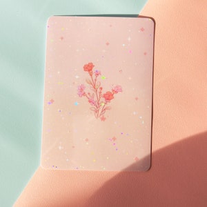 Puede incluir: Una tarjeta rosa con un dise&ntilde;o floral y un fondo brillante. Las flores son rosas y blancas y tienen un aspecto delicado y caprichoso.