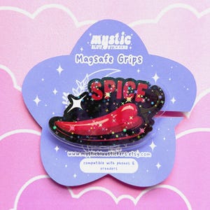 May include: A Magsafe grip featuring a red chili pepper design with the word "SPICE" in red letters. The grip is on a purple, star-shaped backing with the text "mystic blu stickers" and "compatible with phones & ereaders".