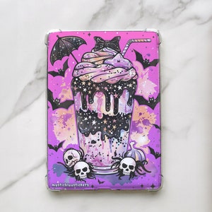 May include: A clear phone case featuring a purple and black illustration of a spooky milkshake with bats, skulls, and stars. The case has a clear border and the text "mysticbluustickers".