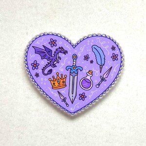 Pode incluir: Um autocolante em forma de coração com fundo roxo e borda ondulada. O design apresenta um dragão roxo, uma espada, uma coroa, uma pena, um frasco de poção e pequenas flores. O autocolante é de tema fantasia.