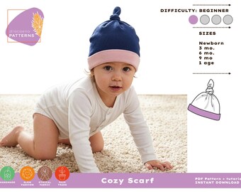 Pode incluir: Um bebê usando um gorro azul marinho e rosa, engatinhando em um tapete bege. A imagem inclui o texto "Cozy Scarf" e "Newborn, 3 mo., 6 mo., 9 mo., 1 age". O nível de dificuldade é iniciante.