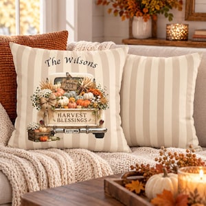 May include: A square throw pillow with beige and white vertical stripes. The center features a vintage truck illustration carrying pumpkins, wheat, and flowers. Text reads The Wilsons, Pumpkin Patch, Harvest Blessings, and Autumn on the truck.