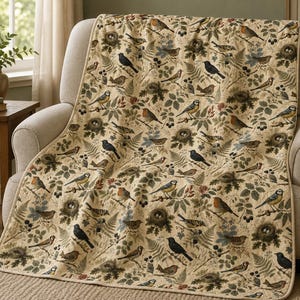 Könnte beinhalten: Eine cremefarbene Wohndecke mit einem durchgehenden Druck von verschiedenen Singvögeln, Vogelnestern und grünen Farnblättern. Die Decke hat einen eingefassten Rand in hellem Beige und zeigt ein wiederkehrendes Muster aus Vögeln in Blau-, Braun- und Schwarztönen.