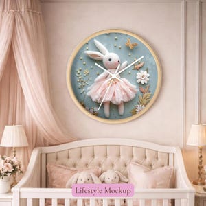 May include: A round wall clock with a light blue face features a white bunny wearing a pink tutu. The clock has gold hands and a gold frame. Decorative butterflies and flowers surround the bunny. The clock is displayed in a nursery setting.