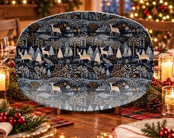 May include: An oval serving platter featuring a repeating pattern of white deer, golden trees, and snowy landscapes against a dark navy blue background. The platter has a smooth, glossy finish and is displayed on a wooden stand.