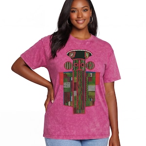 K&ouml;nnte beinhalten: Ein kurz&auml;rmeliges, s&auml;uregewaschenes magentafarbenes T-Shirt mit einem zentralen Grafikdruck. Das Design zeigt eine stilisierte, totemartige Figur in Schwarz, Gr&uuml;n, Rot und Wei&szlig;, die aus geometrischen Mustern, feinen Linien und kleinen Kreisen besteht.