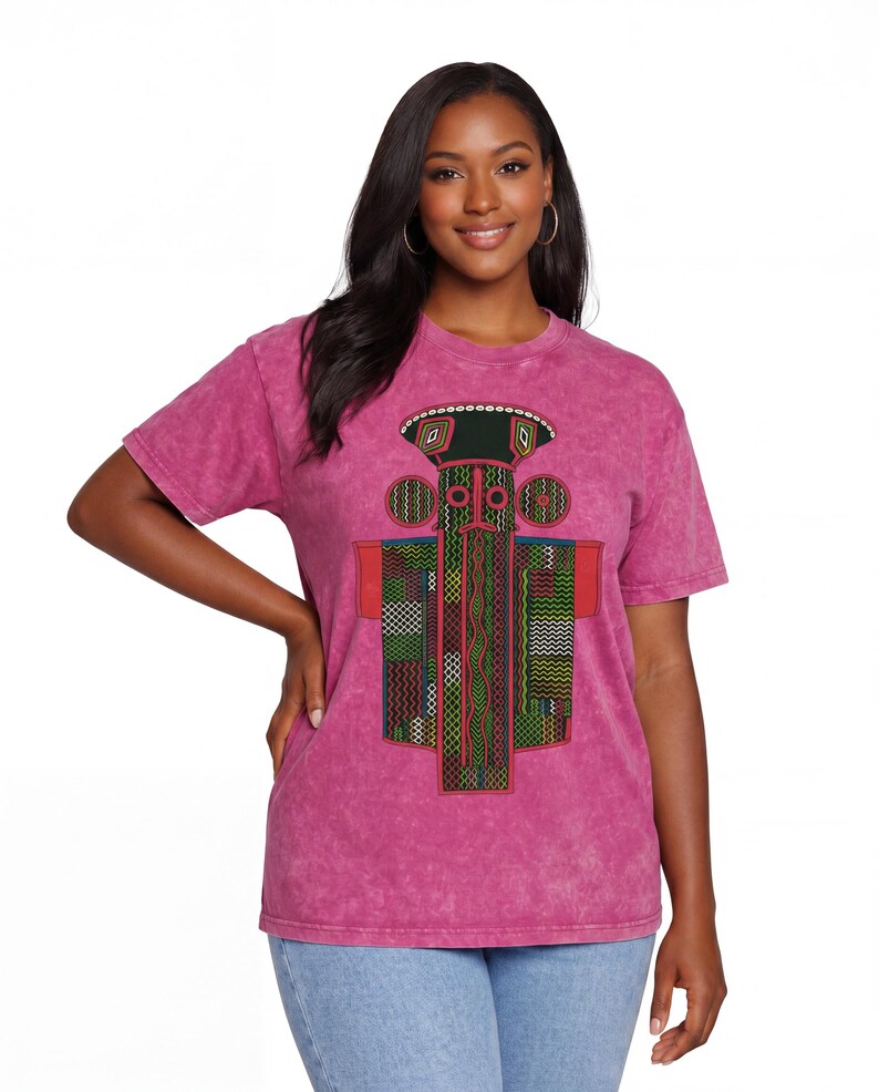 K&ouml;nnte beinhalten: Ein kurz&auml;rmeliges, s&auml;uregewaschenes magentafarbenes T-Shirt mit einem zentralen Grafikdruck. Das Design zeigt eine stilisierte, totemartige Figur in Schwarz, Gr&uuml;n, Rot und Wei&szlig;, die aus geometrischen Mustern, feinen Linien und kleinen Kreisen besteht.