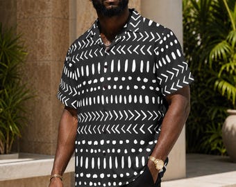 May include: A short-sleeved button-down shirt in black with a white hand-painted style pattern featuring horizontal rows of chevron arrows, vertical dashes, and dots. The shirt has a classic collar, a front button placket, and a straight hemline.