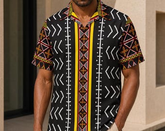 May include: A short-sleeved button-down shirt featuring a black base with a repeating white chevron pattern, a central vertical yellow stripe with red and black geometric accents, and a matching patterned collar, paired with beige trousers.