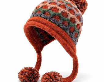 May include: A knitted winter hat with a diamond pattern in shades of orange, green, and grey. The hat has ear flaps with pom-poms and a large pom-pom on top. The hat is designed to keep the wearer warm in cold weather.
