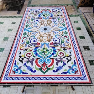May include: A rectangular mosaic table with a colorful floral design. The table features a white background with red, blue, green, and purple floral patterns. The table is supported by four wooden legs.