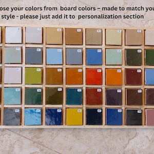 May include: A wooden display case with 42 square tiles in a range of colours. Each tile is set within a small wooden frame, arranged in a grid. The text at the top says, "Choose your colours from board colours - made to match your style - please just add it to personalization section."