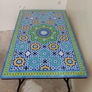May include: A rectangular table with a blue, green, and yellow mosaic tile top. The table has a black metal frame.